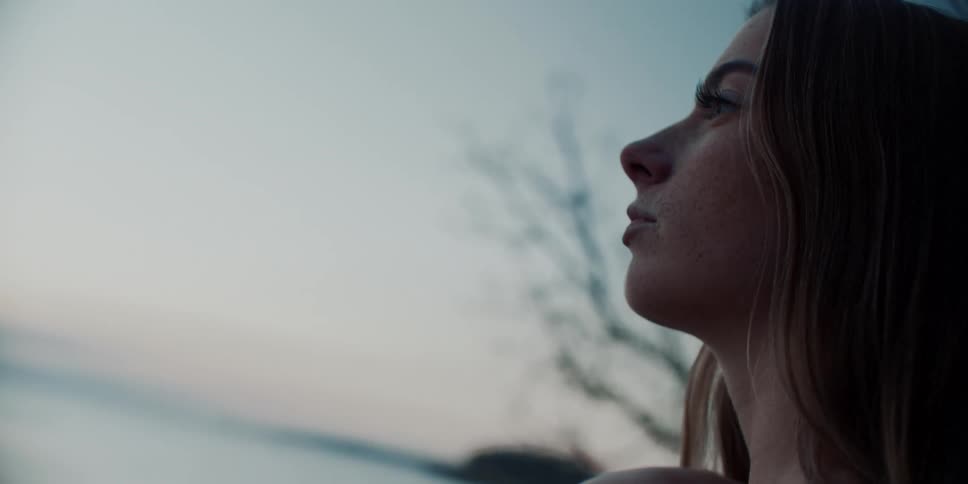 Woman with brown hair and freckles stares ahead