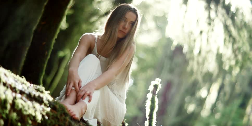 A young woman sits in a forest