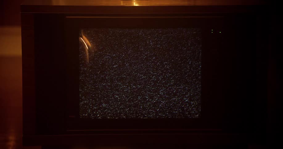 A broken television with a fuzzy screen plays in a home