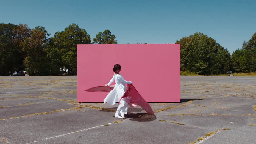 A woman dances in the parking lot waving flags