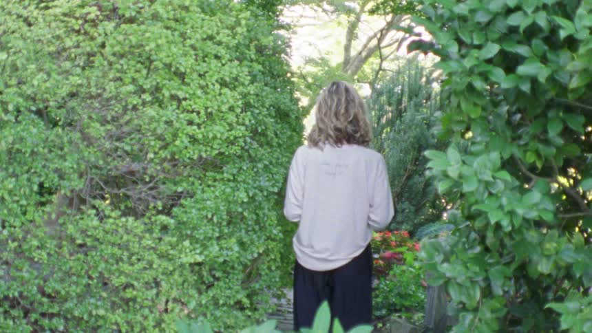 Woman walks on a rock path through a beautiful green garden