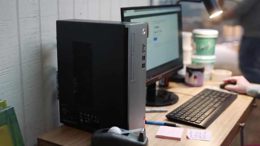 A woman sits at her desk and works as someone walks past