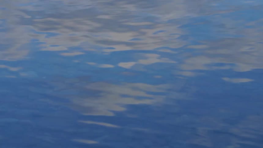 Clouds on a blue sky reflecting on the surface of clear water in a lake