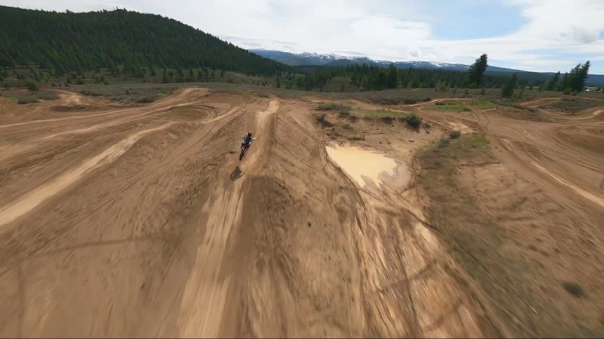 A person rides a dirt bike on a rural dirt track