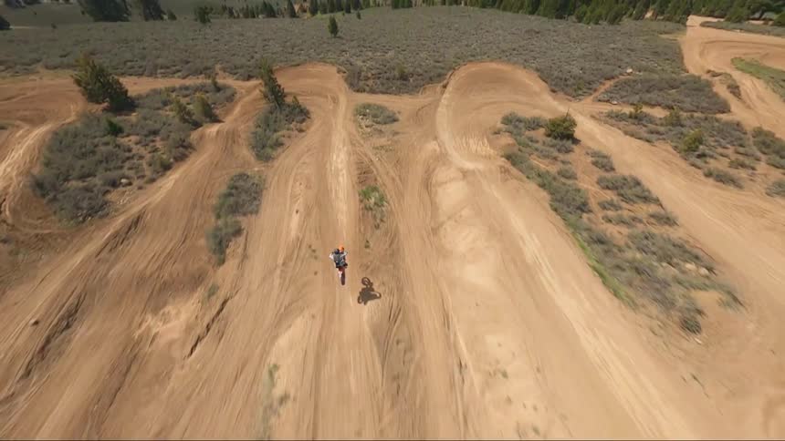 A dirt bike races jumps on a hill