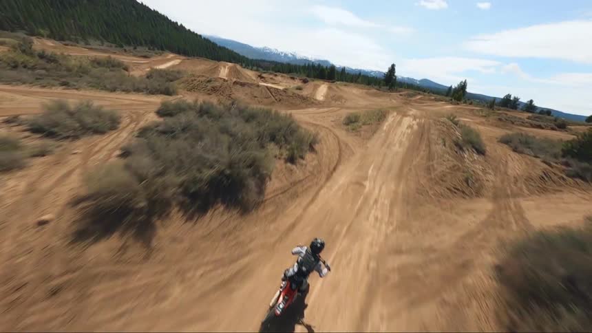 The person on the dirt bike races and jumps over the hills