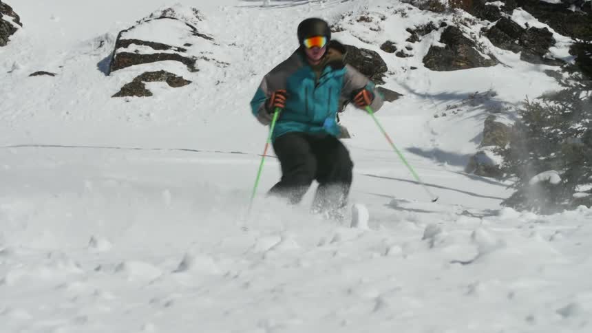 A person with a winter coat goggles and a helmet skiing down a slope