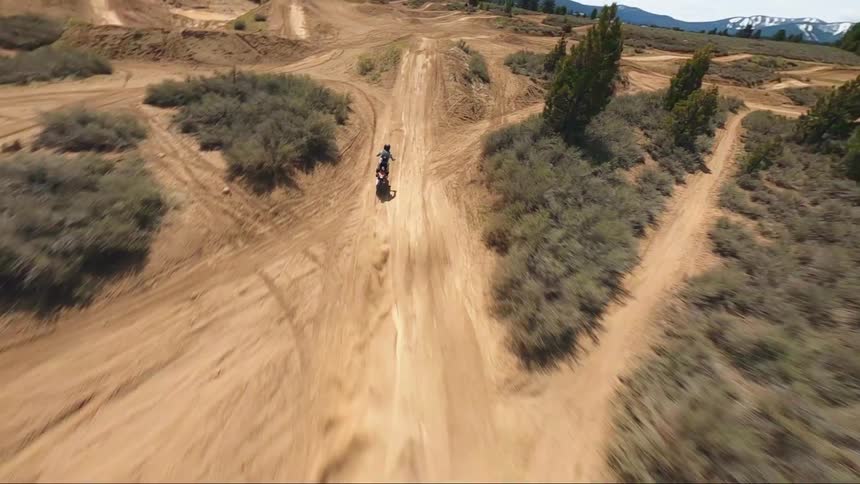 A person rides a dirt bike on a dirt road in a rural area