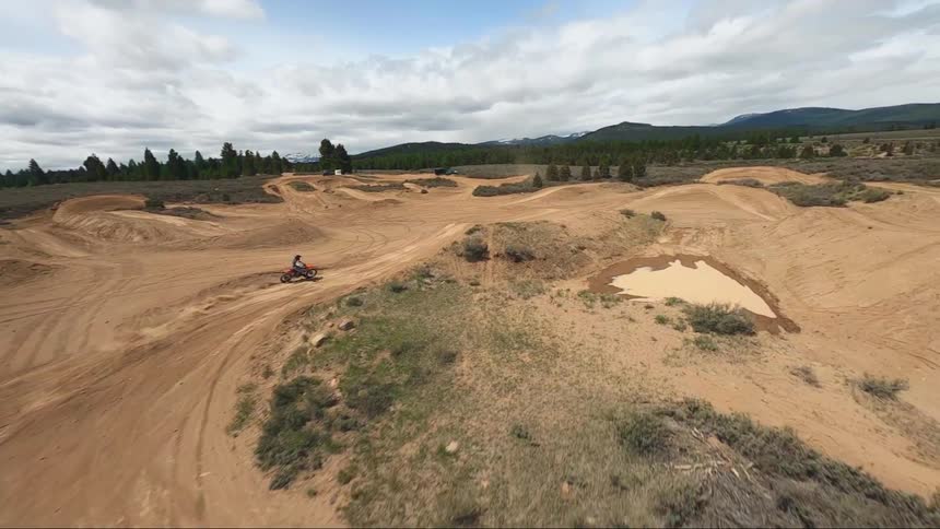 Aerial of a motorcylcle riding on a dirt track out in the countryside