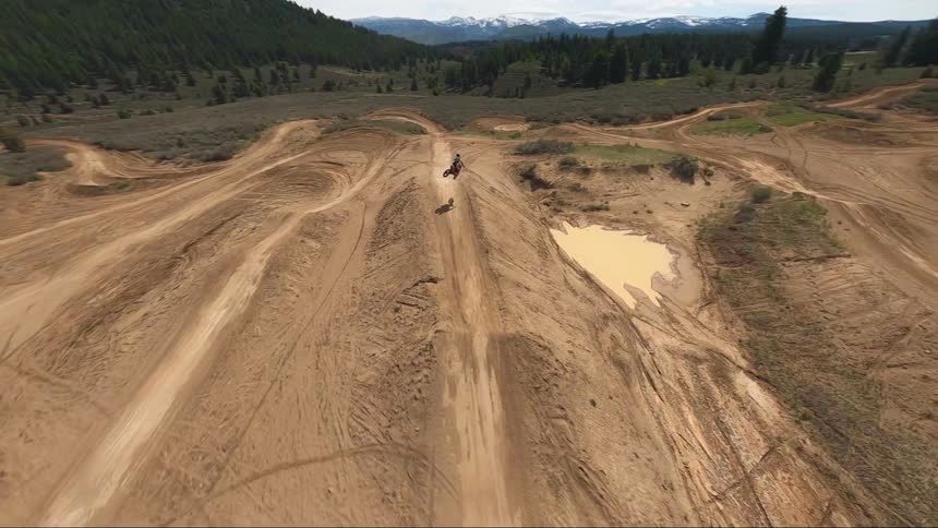 A person riding their motorbike over dirt jumps and hills