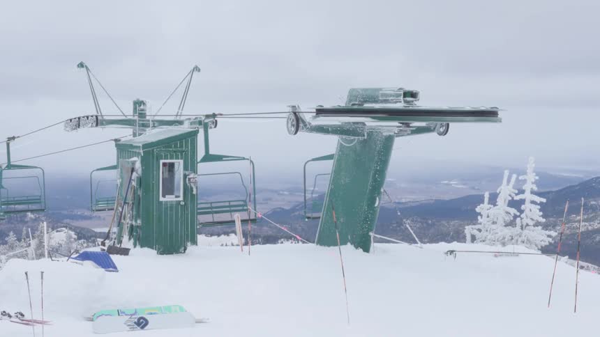 Ski lift chairs travel around the tower at the top of a mountain