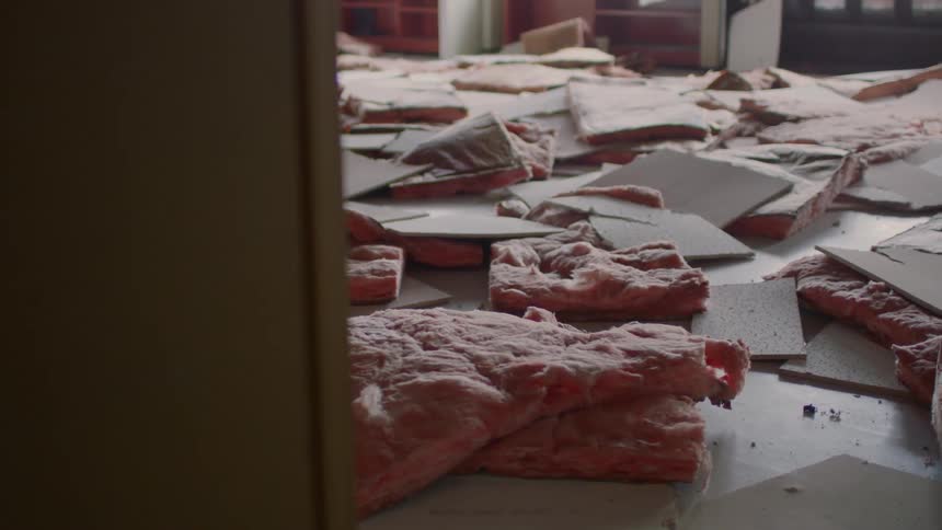 Pink insulation and ceiling tiles scattered across room
