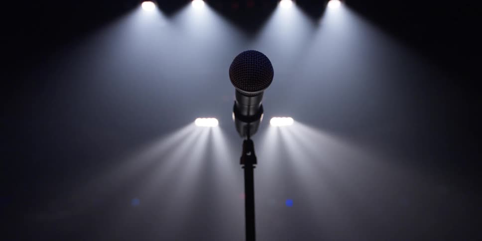 Microphone sits on a stand with spotlights shining behind it