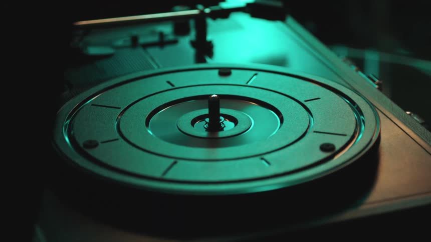 Bluegreen light shining onto a modern record player in a dark room