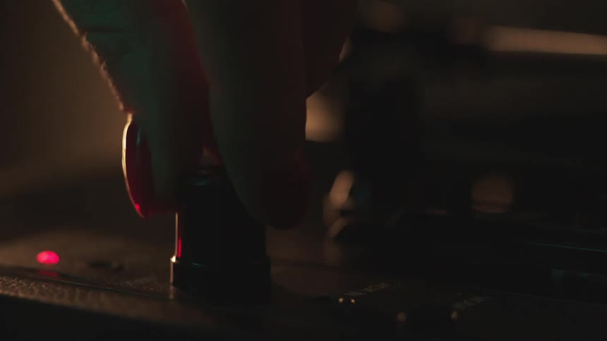 Person wearing red fingernail polish adjusts dial on electronics