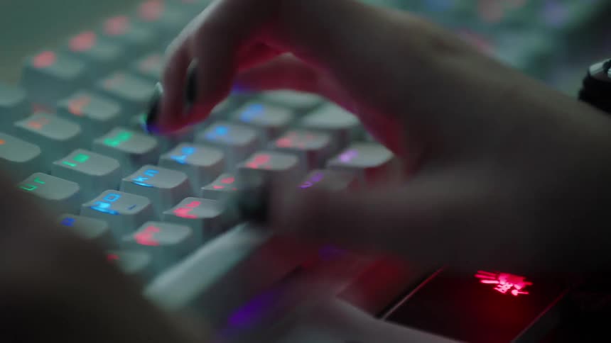 Woman with manicured fingernails type on an rgb backlight keyboard