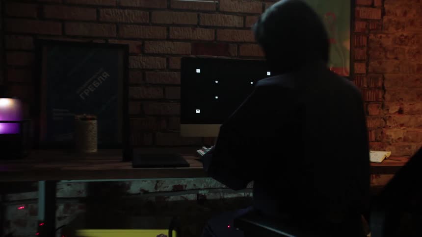 A white person walks over to a desk and starts typing on a computer