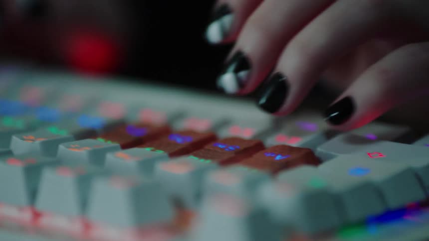 Well manicured hands typing on rainbow backlit keyboard