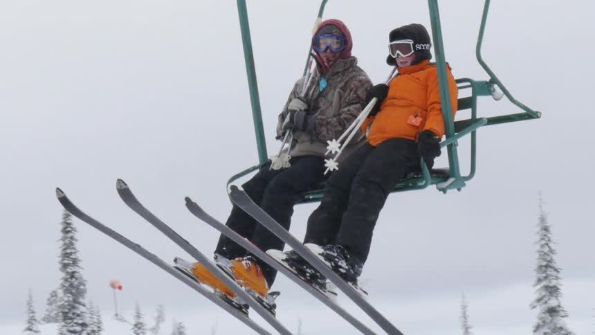 A man and woman riding a ski lift