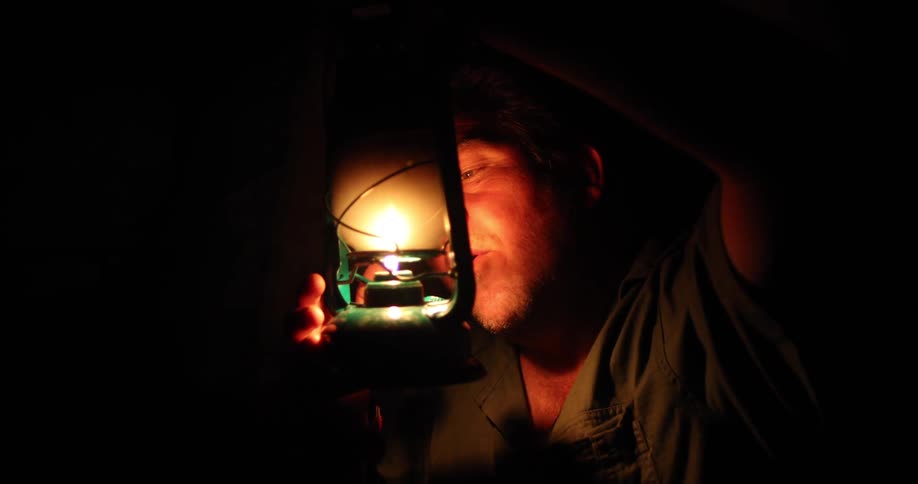 A man blows out the flame in a metal lantern