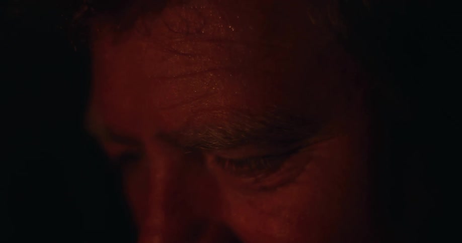 Close up of a man eyes and brow under a red light in a dark environment