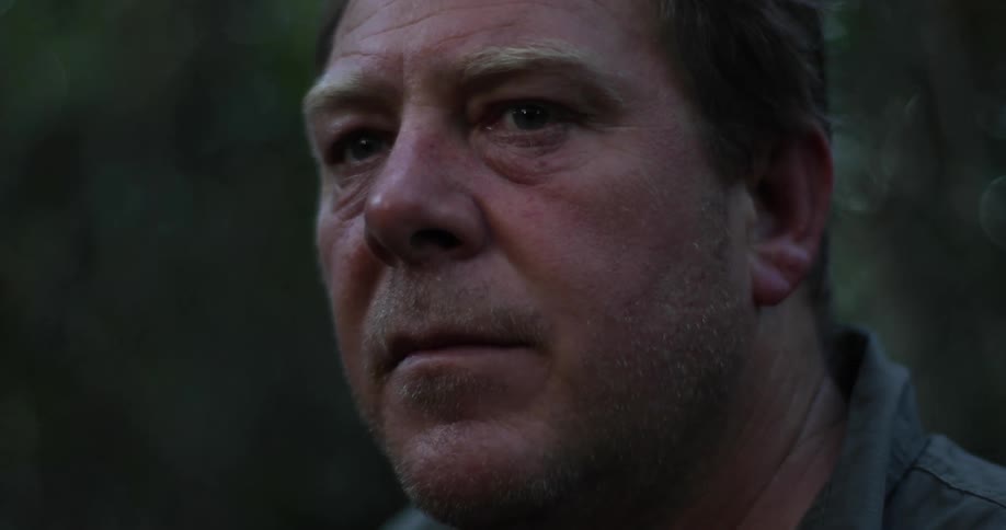 Middle aged white man looks around in the forest at dusk