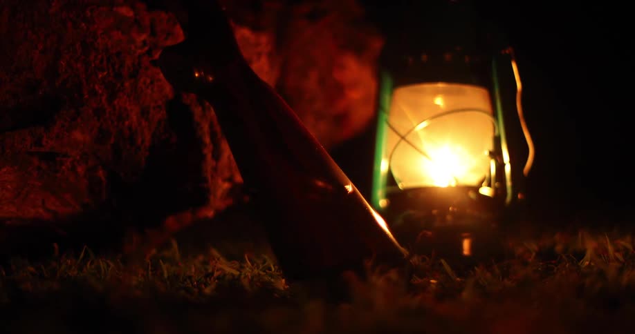 A lantern sitting on the ground next to a rock