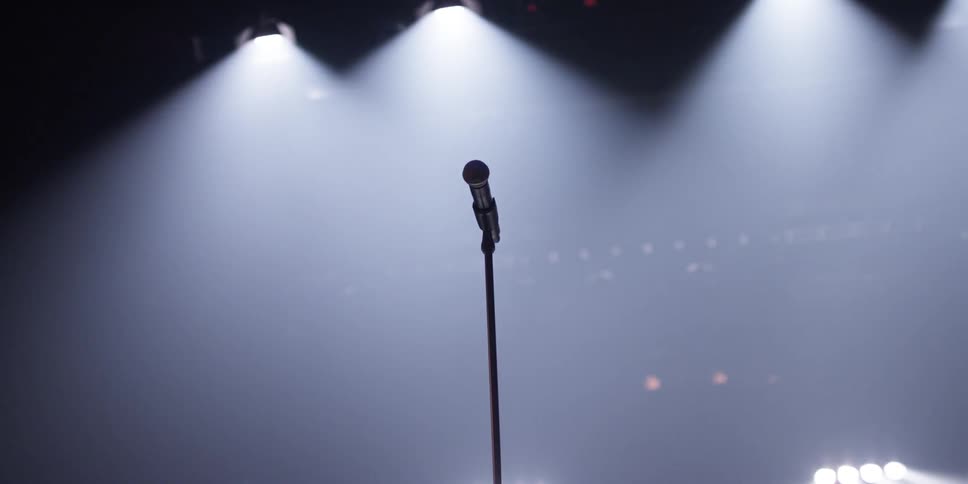 A microphone on a stage with bright lights shining