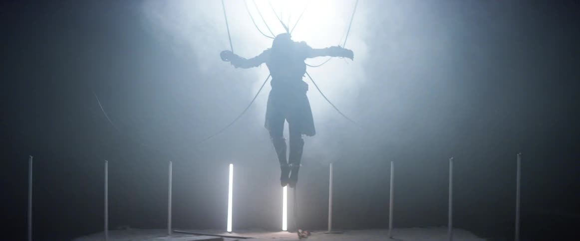 Person hanging by cables is illuminated briefly by lights