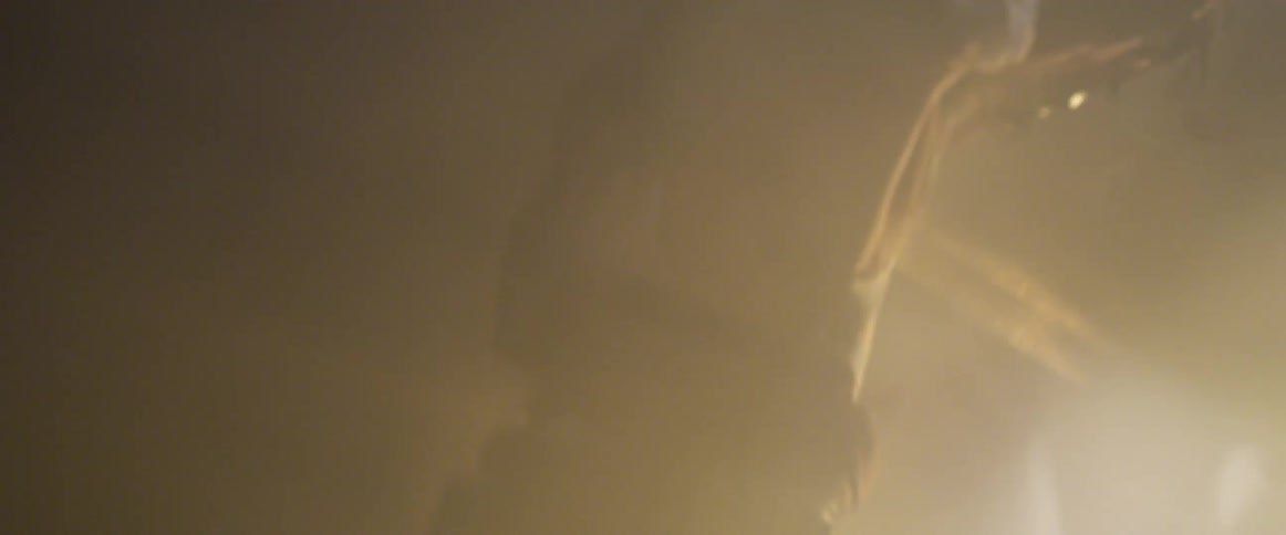 Man wearing robes run in place in front of flashing gold lights