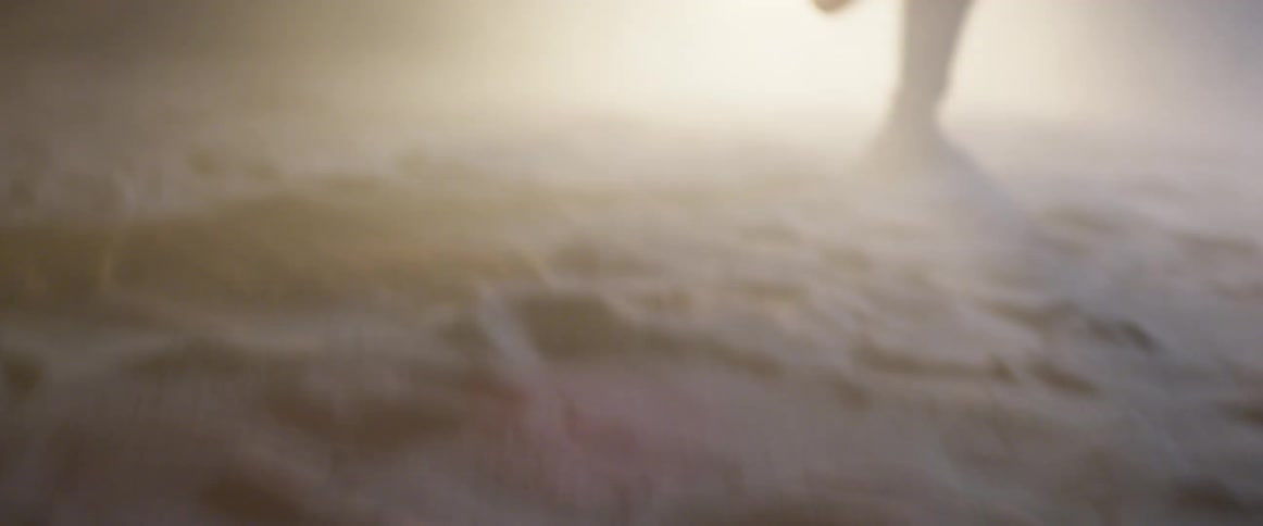 Person running through sand towards car headlights at night