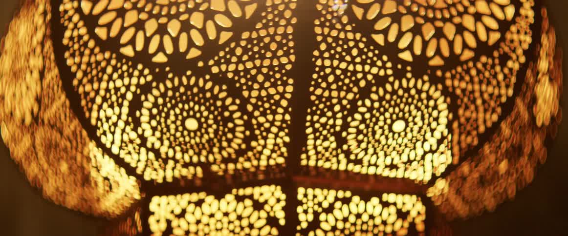 Light shines from within a metal chandelier with cutout circles