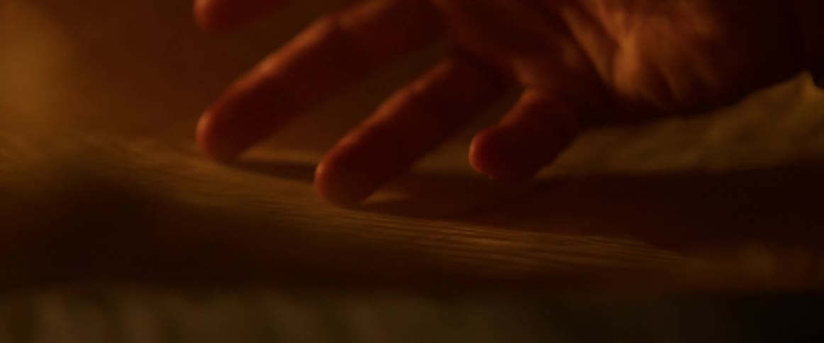 Fingers graze the surface of a paper with designs on it