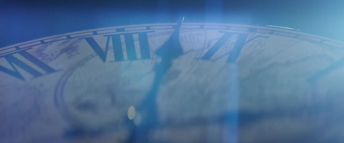 Clock hand traveling around face of clock with roman numerals