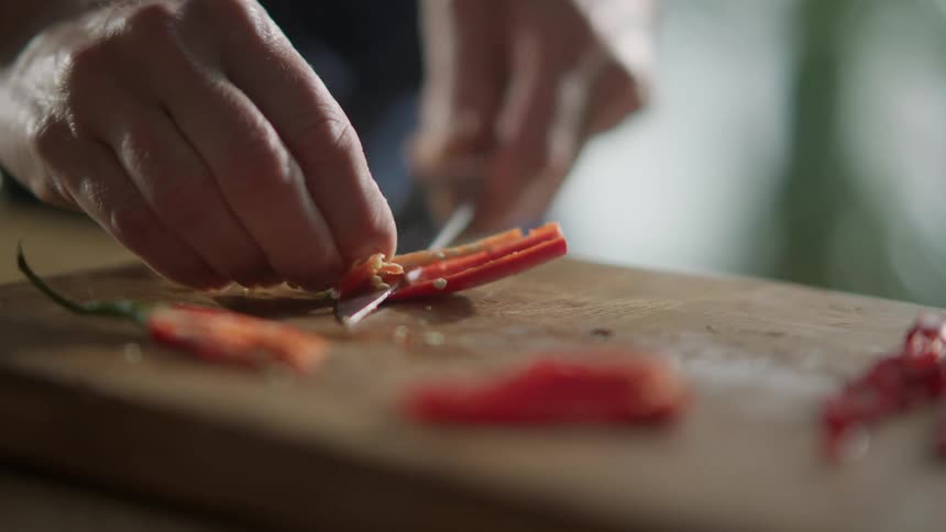 A man removes the seeds and middle section from chili peppers