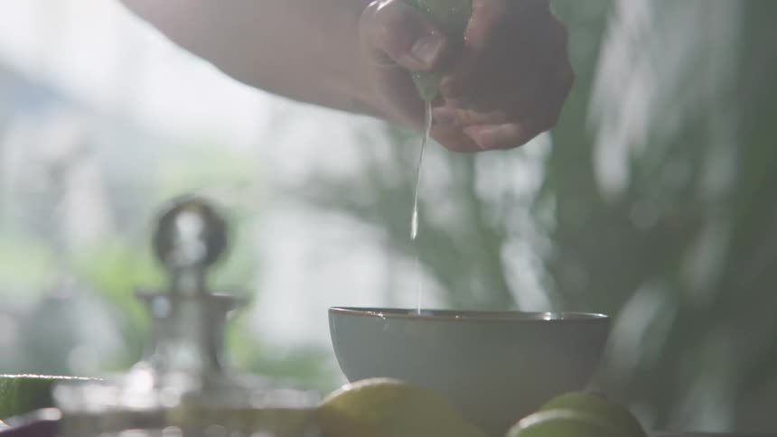 A white man squeezes juice from a lime into a bowl
