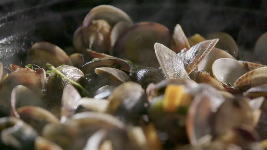 Pan of steamed clams cooking in a bubbling liquid
