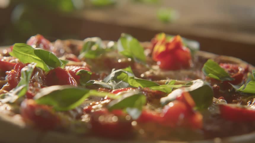 Person spreads basil leaves on pizza