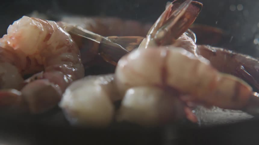 Shrimp falling on hot oil in a pan ready to be cooked