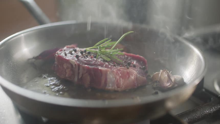 A piece of meat being cooked in a pan