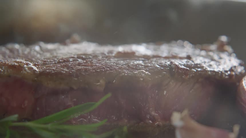 A piece of meat being turned and cooked