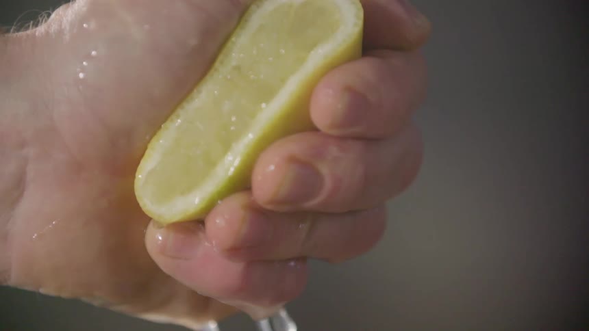 Close up of a hand squeezing juice out of a lemon