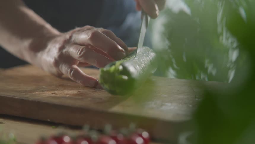Zucchini is sliced lengthwise on a wooden cutting board