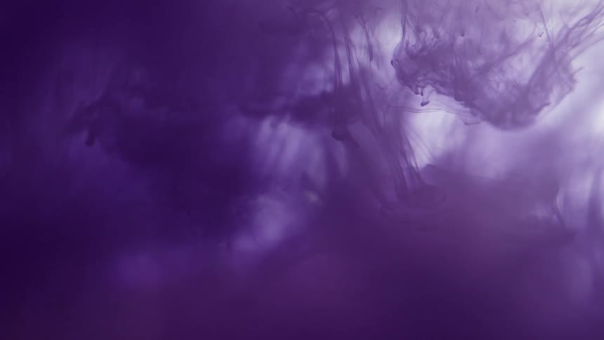 Colorful purlple ink floating down a tank of water
