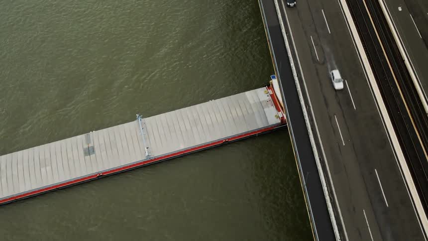 A shipping boat passes under a large bridge