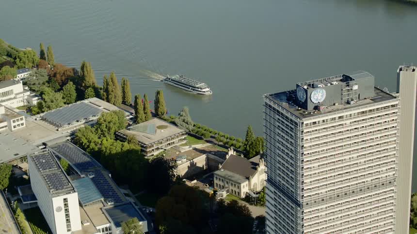 A passenger ship travels down a waterway past an urban area