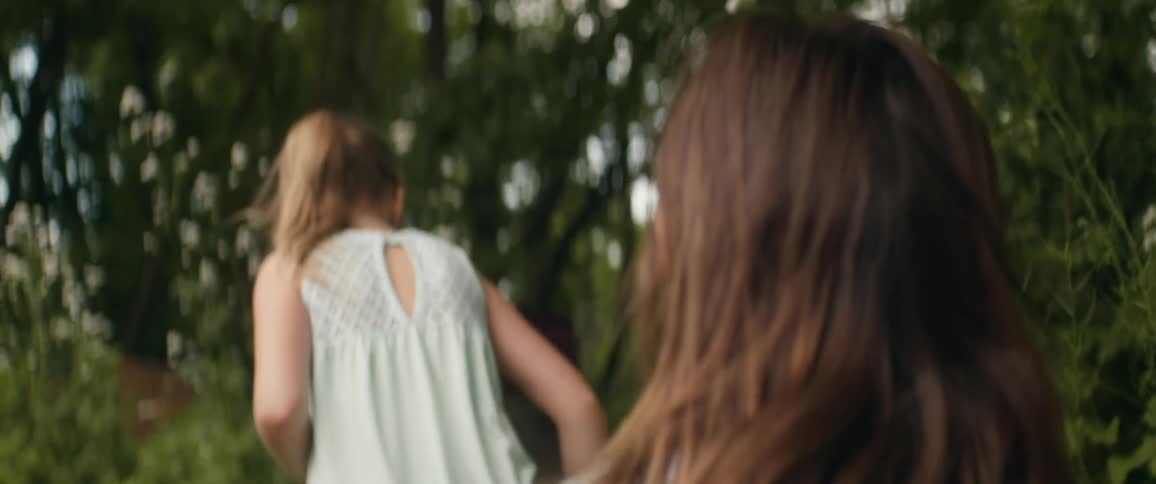 Girl with brown hair follows blonde girl with ponytail in the forest