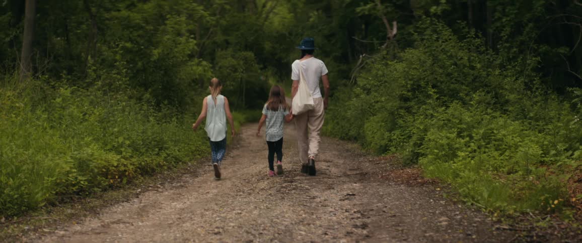 A mother down a path in a forest with her two daughters