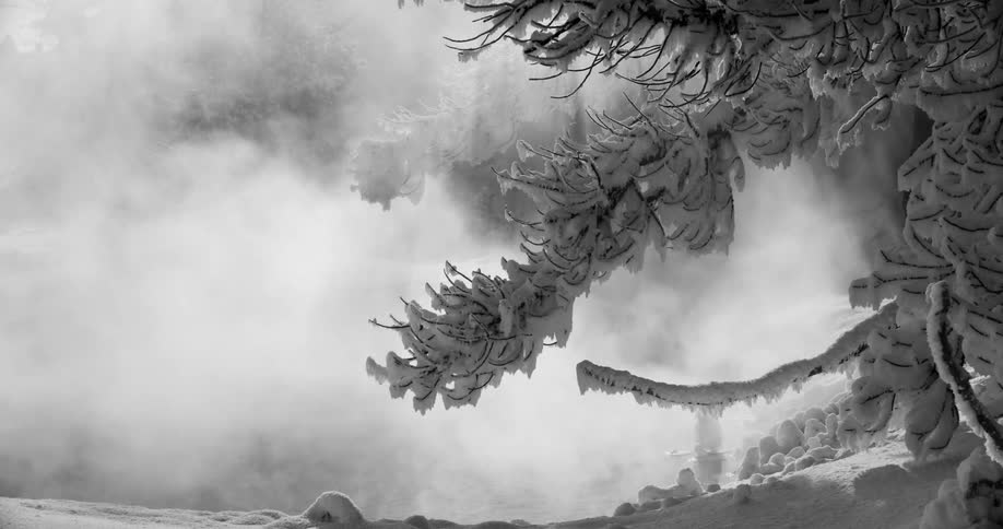 Steam emerging from a bubbling hot spring in a snowy countryside