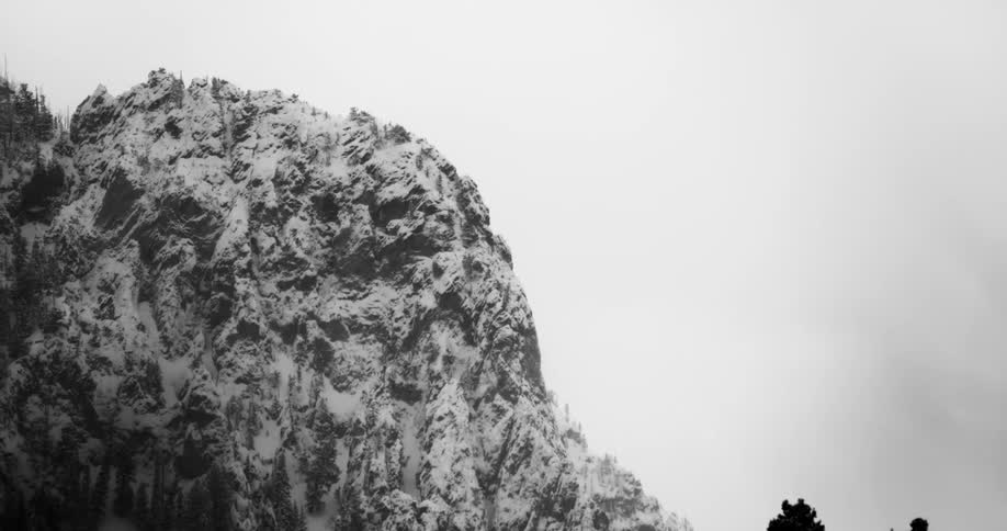Snow covers craggy mountain under overcast sky